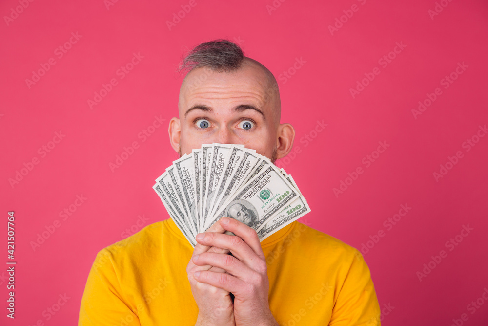 European man on pink red background with fan on 100 dollars shocked excited amazed isolated space European man on pink red background with fan on 100 dollars shocked excited amazed isolated space