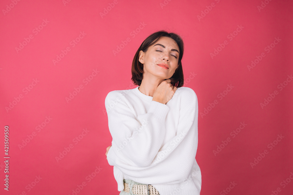 Beautiful woman in casual white sweater on pink red background love concept, holding hands crossed hugging herself isolated copy space closed eyes Beautiful woman in casual white sweater on pink red background love concept, holding hands crossed hugging herself isolated copy space closed eyes