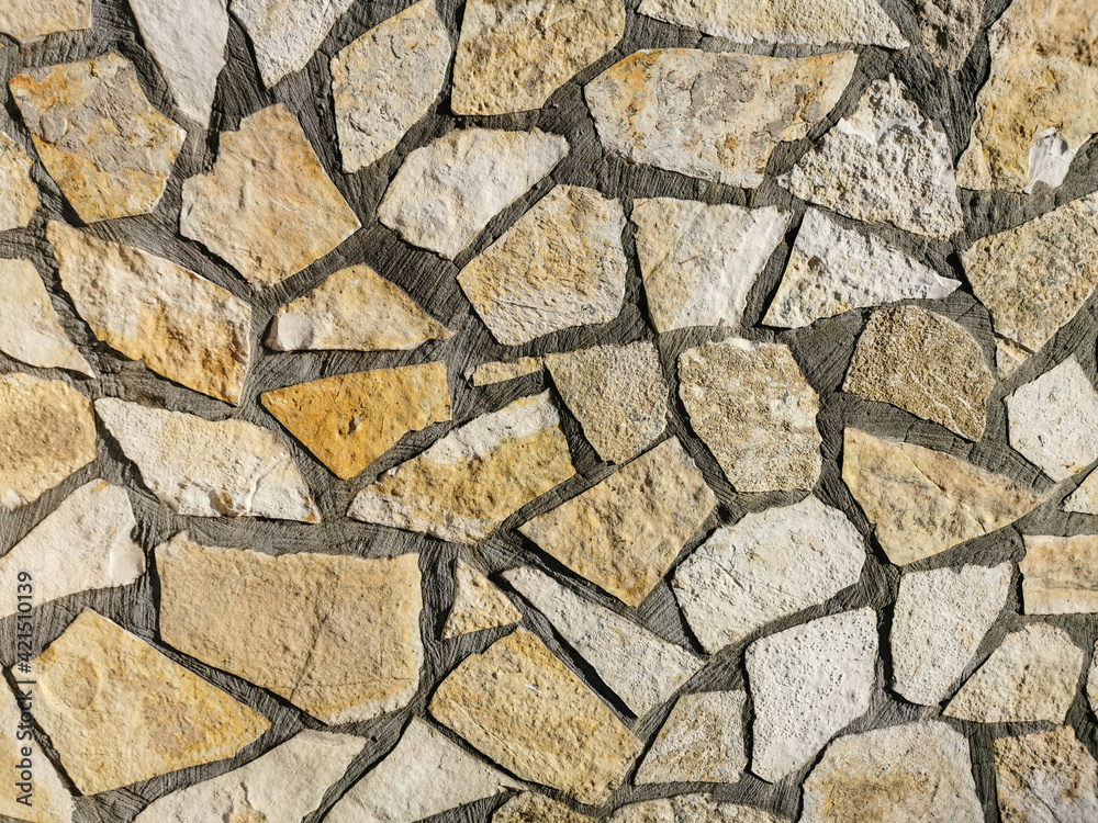 Fototapeta premium Stone masonry wall surface. Rock pieces and concrete mosaic wall background. Rough stone textured background. Brickwork backdrop.