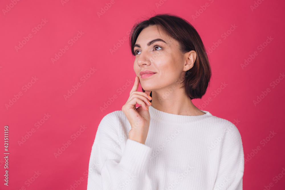 Beautiful woman in casual white sweater on pink red background looks to the side thoughtfully with a sweet smile isolated copy space Beautiful woman in casual white sweater on pink red background looks to the side thoughtfully with a sweet smile isolated copy space