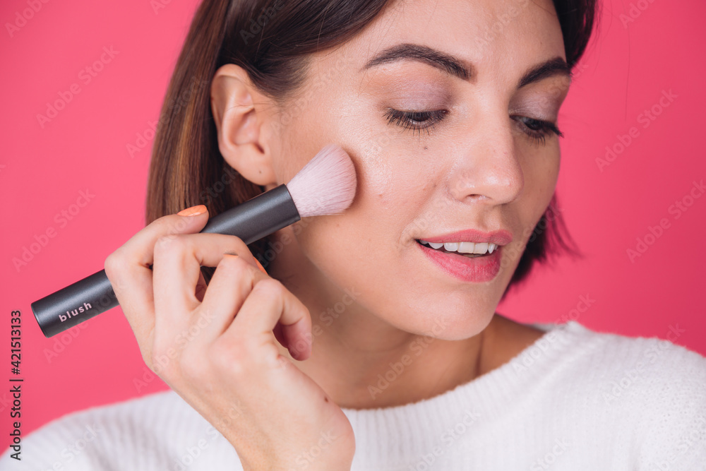 Woman in casual white sweater on pink red background with makeup on face hold blush brush isolated copy space beauty portrait Woman in casual white sweater on pink red background with makeup on face hold blush brush isolated copy space beauty portrait
