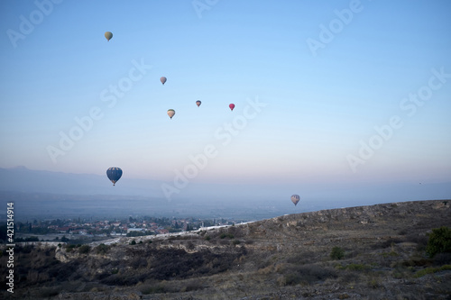 Multicolored hot air balloons flying in sunrise sky.