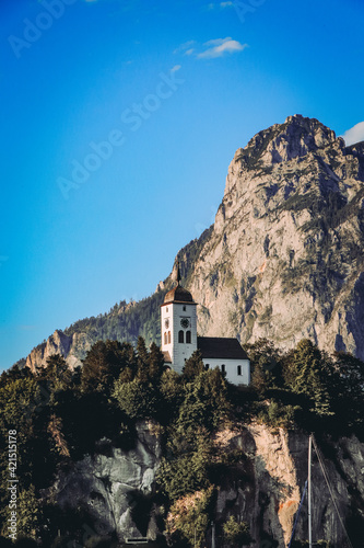 small Christian church in the west of Austria near the town of Innsbruck, which rises on a hill and has a huge rock behind it. Dangerous output. Protected from enemies © Fauren