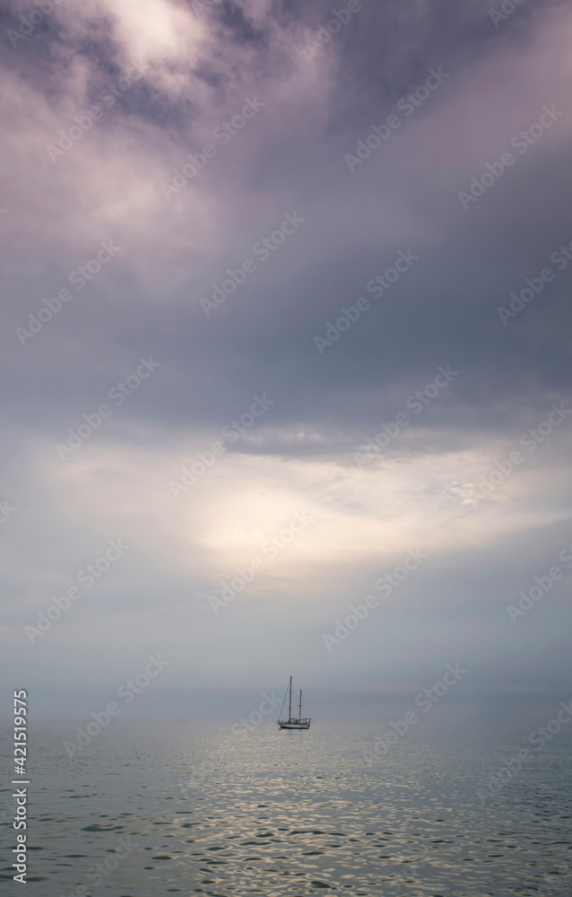 a small sailboat stranded in the middle of a sea in total calm in a sunset with a cloudy sky in mauve tones, feeling of calm, isolation, minimalism and loneliness, space to copy vertical a small sailboat stranded in the middle of a sea in total calm in a sunset with a cloudy sky in mauve tones, feeling of calm, isolation, minimalism and loneliness, space to copy vertical