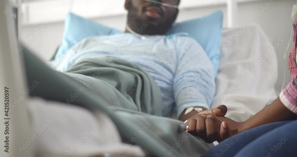 Cropped shot of african wife visiting husband in hospital holding hands and supporting Cropped shot of african wife visiting husband in hospital holding hands and supporting