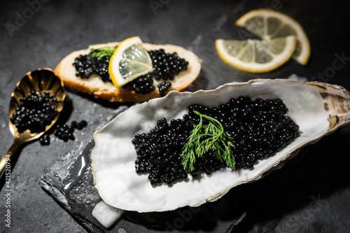 Black caviar in oyster shell on black slate background
