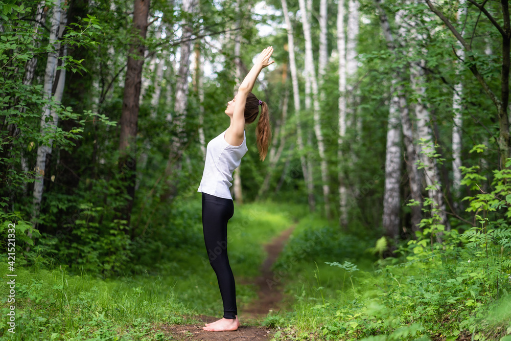 Fit young beautiful woman wearing white top and black sporty leggings working out outdoors in park on summer day Fit young beautiful woman wearing white top and black sporty leggings working out outdoors in park on summer day