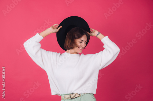 Stylish woman in casual white sweater and hat on pink red background isolated space smile cheerful moving positive