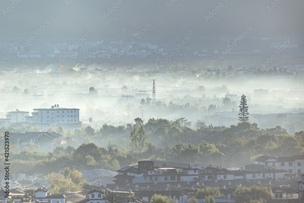 Fog and smoke above city district at sunrise. Lijiang.