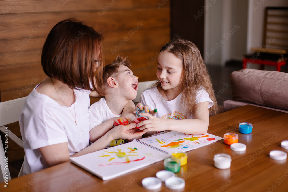 Mother draws with children at home. Development of a child with cerebral palsy. Friendship caring kindness and love. Rehabilitation by creativity. Family with a disabled child. Togetherness lifestyle Mother draws with children at home. Development of a child with cerebral palsy. Friendship caring kindness and love. Rehabilitation by creativity. Family with a disabled child. Togetherness lifestyle