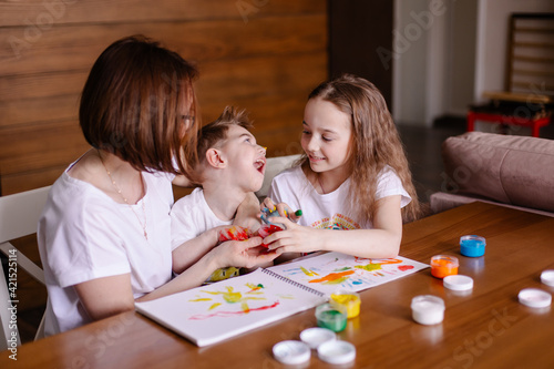 Mother draws with children at home. Development of a child with cerebral palsy. Friendship caring kindness and love. Rehabilitation by creativity. Family with a disabled child. Togetherness lifestyle 