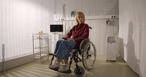 Pensive disabled elderly patient sit on wheelchair alone in hospital room