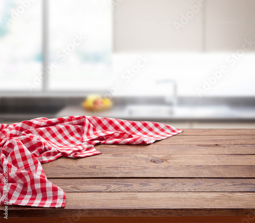 Red checkered tablecloth on wooden table. Napkin close up top view mock up. Kitchen rustic background.
