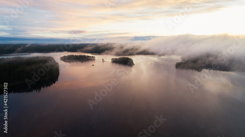 Beautiful sunrise on a foggy forest lake. Early morning with mist above the lake and forest. Drone shot.