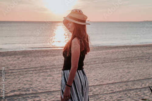 young woman with hat on beach on vacation