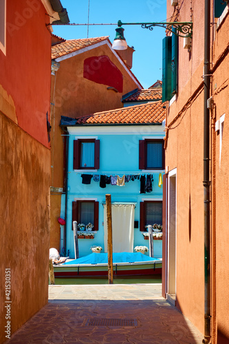 Small street by canal in Burano island in Venice © Roman Sigaev