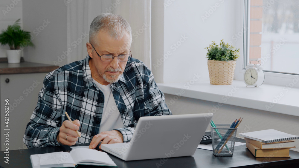 An elderly man keeps financial records at a computer. An elderly man keeps financial records at a computer.