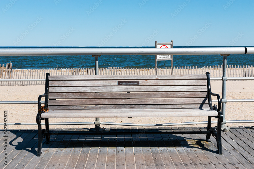 Park bench on boardwalk with beach and water in background Stock Photo |  Adobe Stock