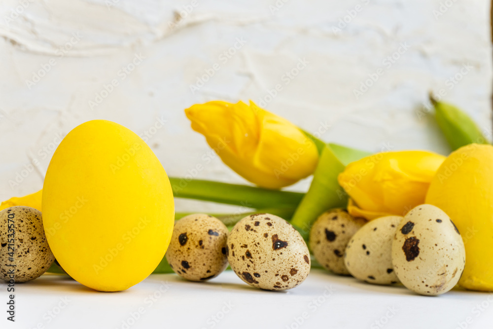 Easter holiday background with yellow chicken eggs, quail eggs and yellow tulips. Easter postcard. Easter and holidays concept.  Copy space. Selective focus.