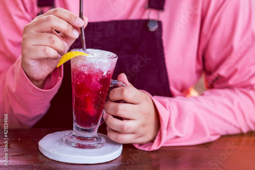 Strawberry drink in a clear glass mixed with lemon yogurt, put on top. And the woman's hand