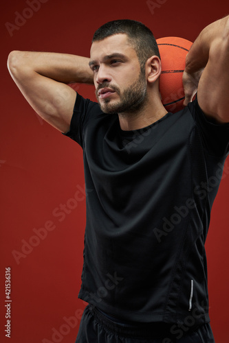 Handsome sportsman in black sportswear posing at the camera isolated on red background © Friends Stock