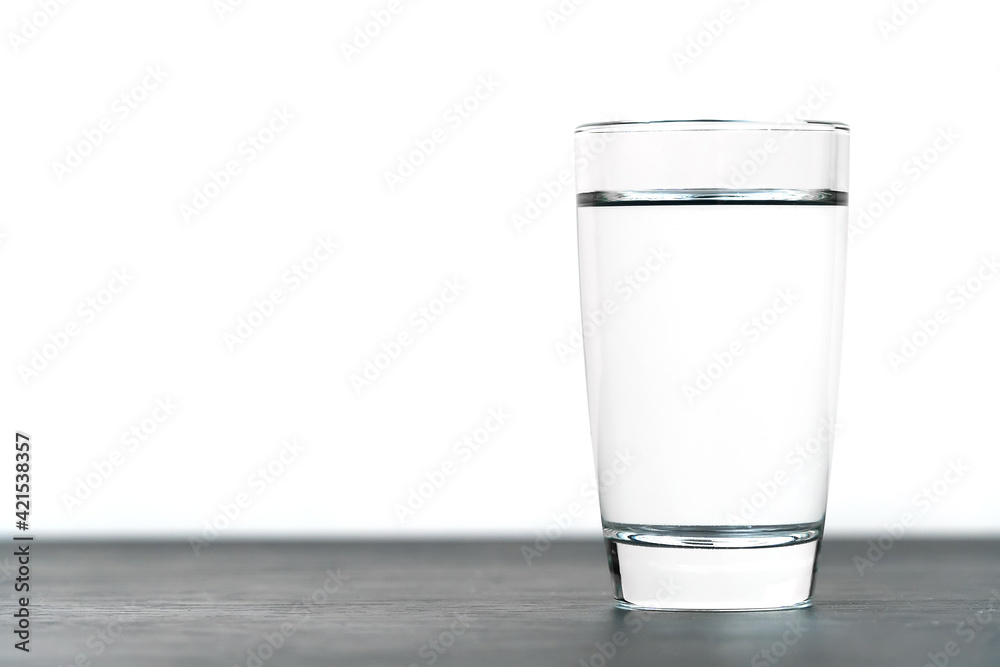 Close-up of a standing vodka glass on a black table on a white background with copy space. Macro Close-up of a standing vodka glass on a black table on a white background with copy space. Macro