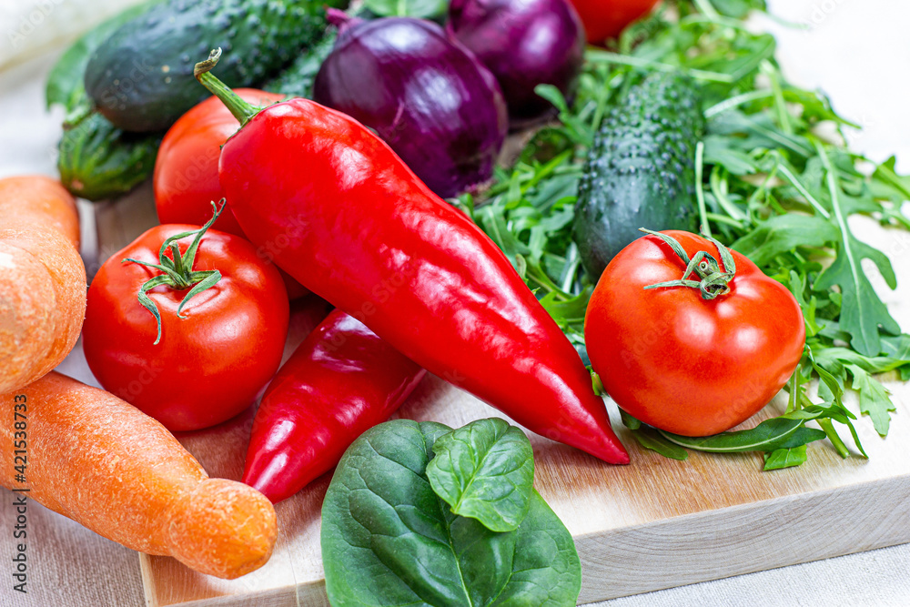 Fresh farm summer vegetables for salad: cucumbers, tomatoes, onions, peppers, arugula leaves in the kitchen on light background. Fresh farm summer vegetables for salad: cucumbers, tomatoes, onions, peppers, arugula leaves in the kitchen on light background.