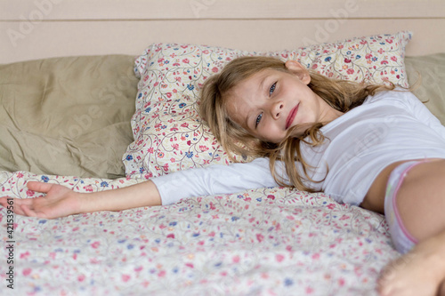 Little girl is resting on the bed.