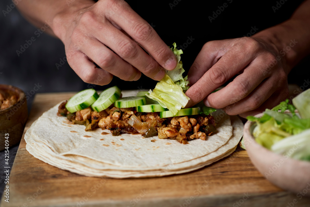 young man fills a durum or a burrito