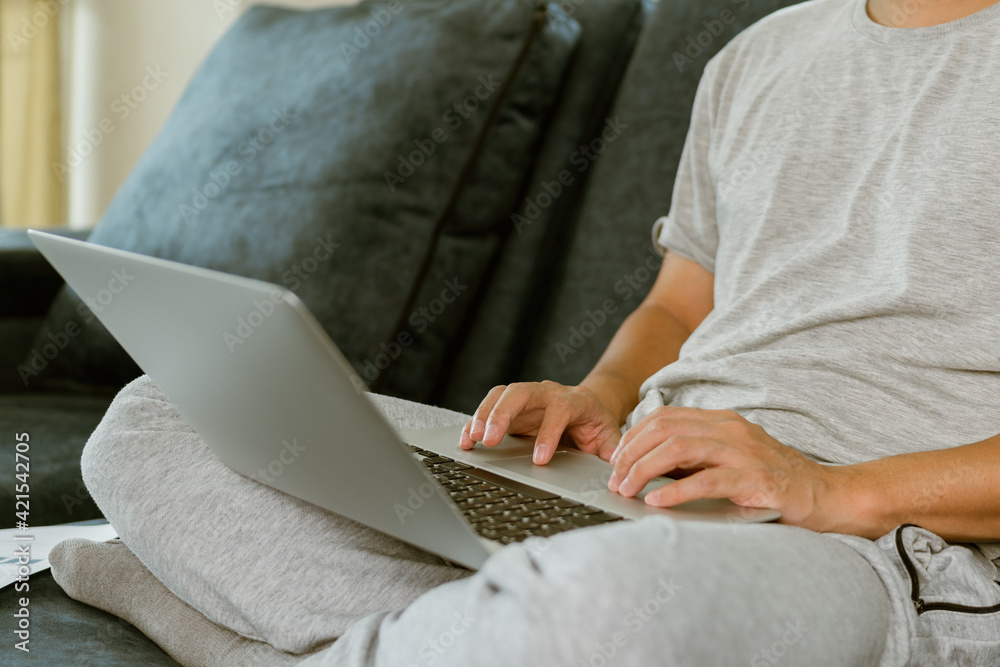 Naklejka premium Close up man hand using laptop for work during quarantine at home.