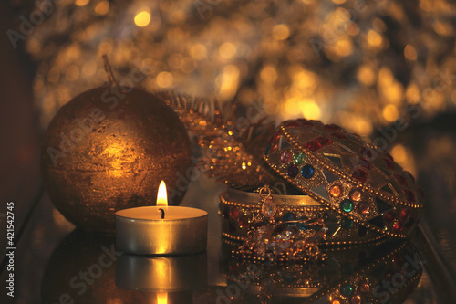 Golden candle and box with gold and jewelry, Luxury christmas decoration, happy new year 2022 and 2023,furtune telling and magic, warm cozy interior,  blured background photo