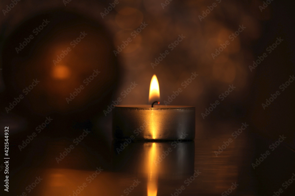 One golden burning candle in the middle of blured background and bokeh, decorations for warm cozy interior, warmth and romanic atmosphere One golden burning candle in the middle of blured background and bokeh, decorations for warm cozy interior, warmth and romanic atmosphere