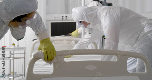 Photography Team in protective suit and mask disinfecting furniture in hospital room from co