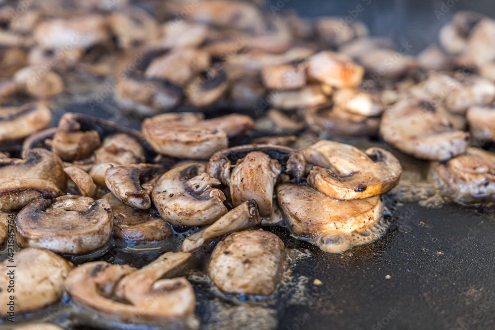 sauteed mushroom slices on an outdoor griddle propane grill in the summer
