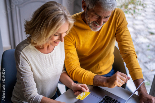 Elevated view of smiling mature couple making online payment with credit card