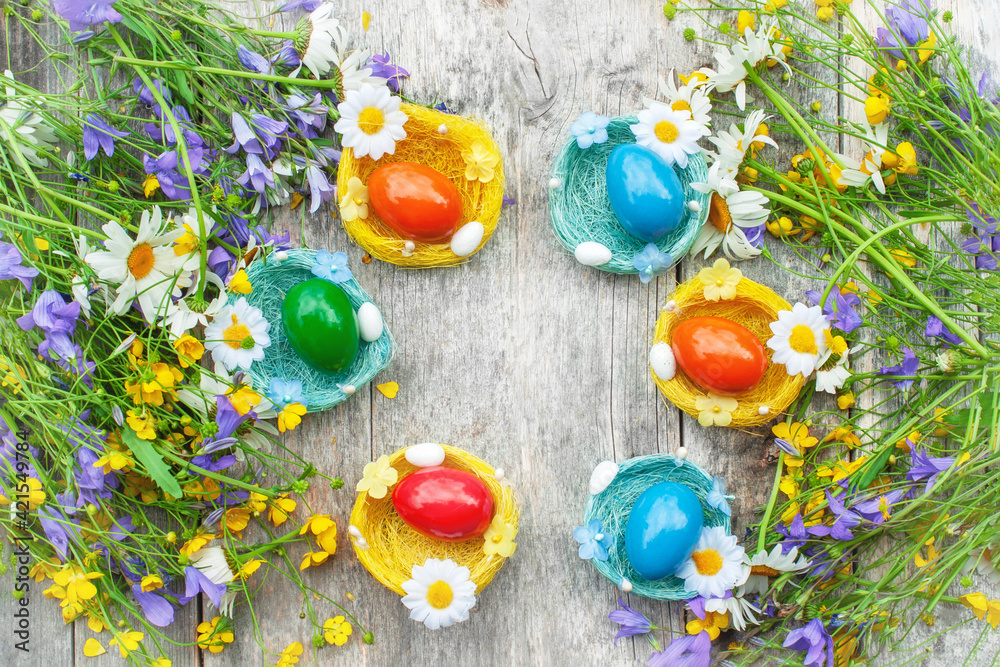 Colorful Easter eggs in the nests of wild wildflowers. Easter decoration in the country style. Horizontal background for Easter greetings. Copy space