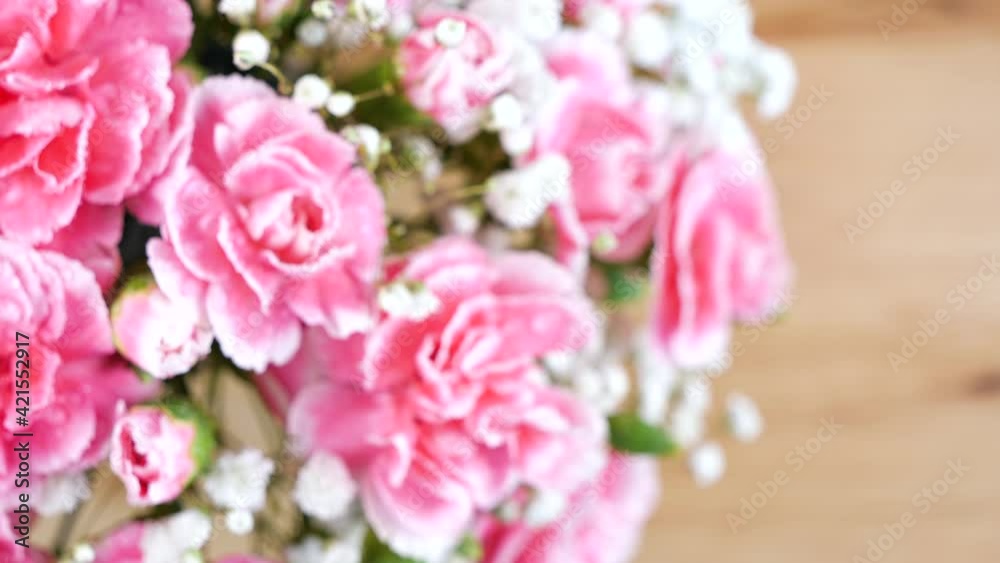 Panning shot of bouquet pink carnation spray flower with water drops on wooden table Panning shot of bouquet pink carnation spray flower with water drops on wooden table