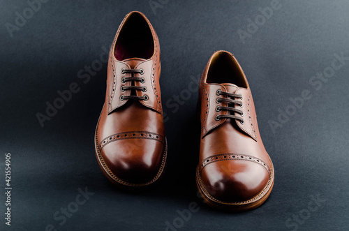 Classic brown perforated shoes on black background. Stylish men's boots