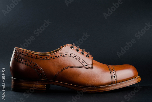 Classic brown perforated shoe on black background