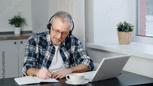 A man wearing headphones participates in online negotiations on a laptop.