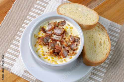 Corn flakes with gratin cheese, fried bacon accompanied by bread on wooden background