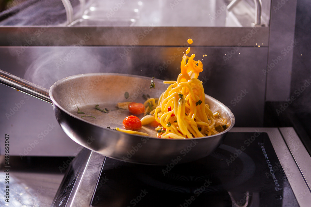 Cooking spaghetti concept. Pasta in the pan. Cooking Fresco Pasta. Italian cuisine, tomato sauce for pasta, healthy food making, detailed view steam in the kitchen. Flipping pasta in the air