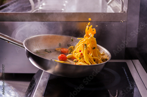 Obraz na płótnie Cooking spaghetti concept. Pasta in the pan. Cooking Fresco Pasta. Italian cuisine, tomato sauce for pasta, healthy food making, detailed view steam in the kitchen. Flipping pasta in the air w salonie