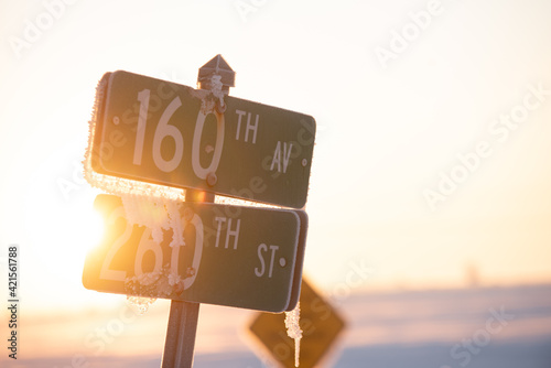 street sign with sunlight backlit and ice with snow