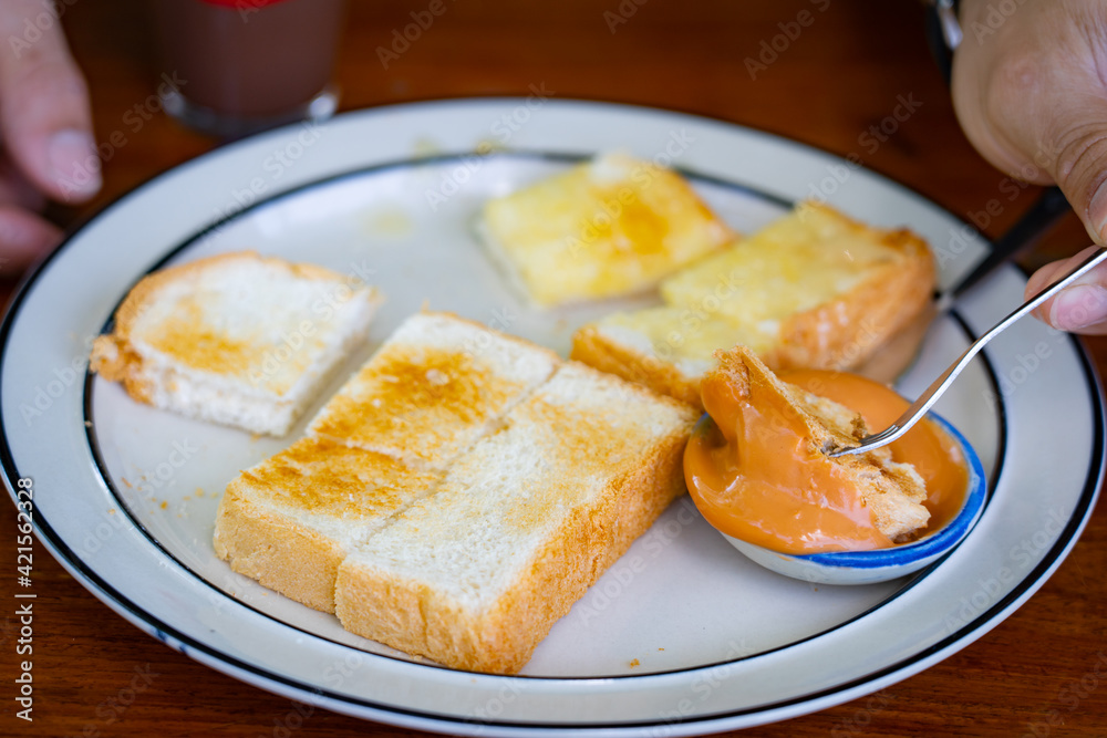 Slices of toast bread and butter with steamed custard in white dish on wooden table. Slices of toast bread and butter with steamed custard in white dish on wooden table.