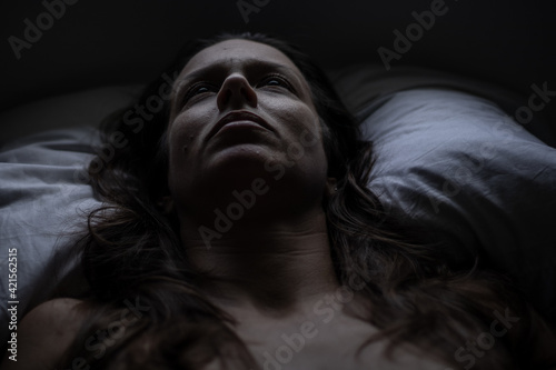 Close do rosto de uma mulher e meia idade deitada na cama. Depressão. Tédio. Solidão.