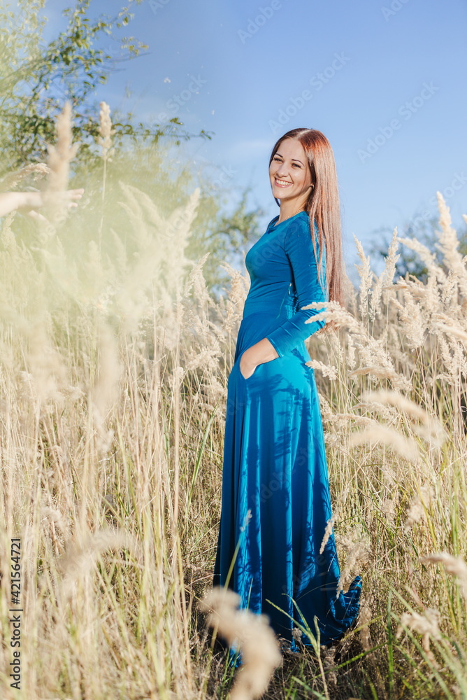 Obraz premium Beautiful girl in a blue dress on a background of nature