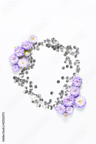 holiday layout. beautiful frame of silver shiny and fresh purple flowers on a white background. space for text