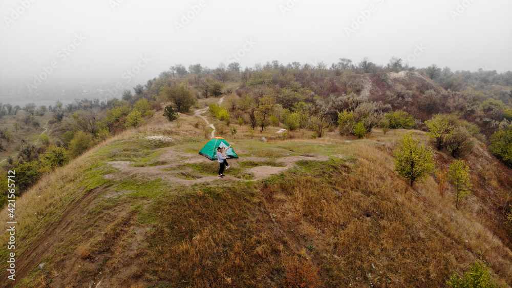 Obraz premium Aerial top view of happy mother and daughter near tent at hill. Active time together