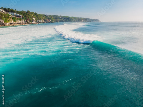 Blue wave in tropical ocean at Padang Padang, drone shot. Aerial view of barrel wave